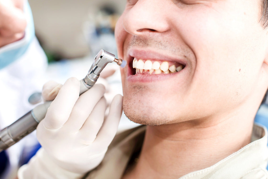 Image of man getting his teeth cleaned at a dental office. 